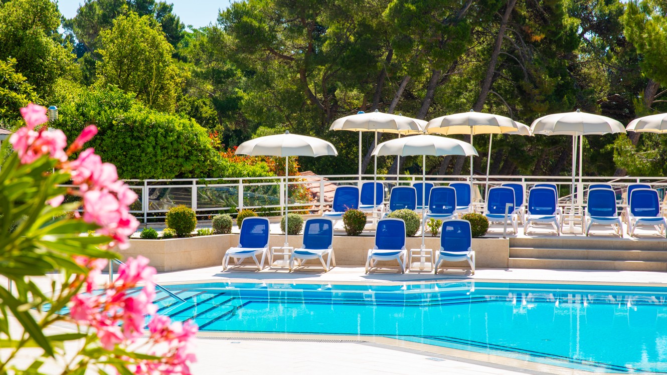 View of the pool with sun umbrellas and loungers in front of the Aminess Vival Grand Azur Hotel, Orebić.
