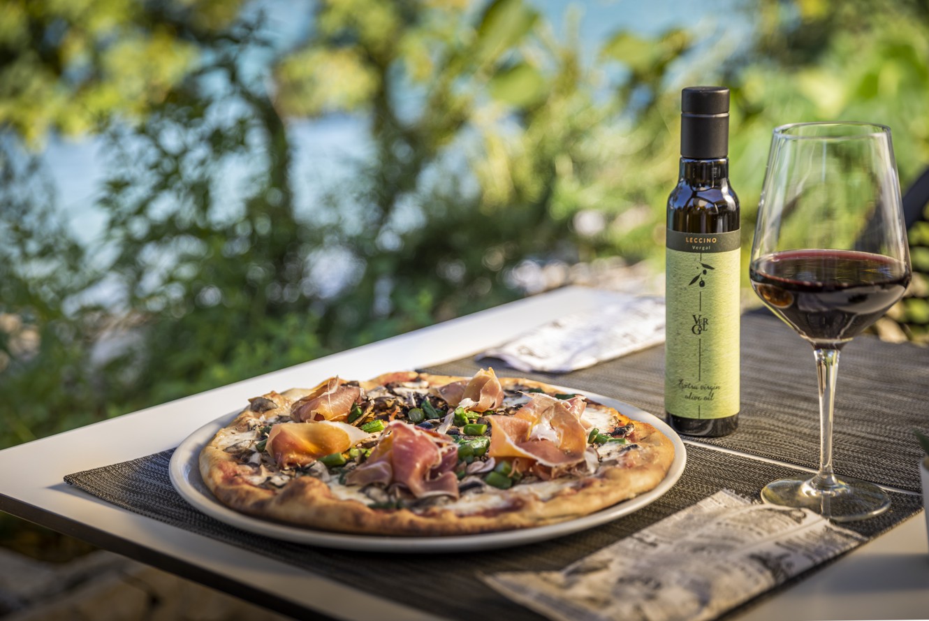 Houtgestookte pizza met levendige toppings, geserveerd met wijn en olijfolie bij Il Cantuccio in de buurt van Aminess Style Camping Atea Resort.