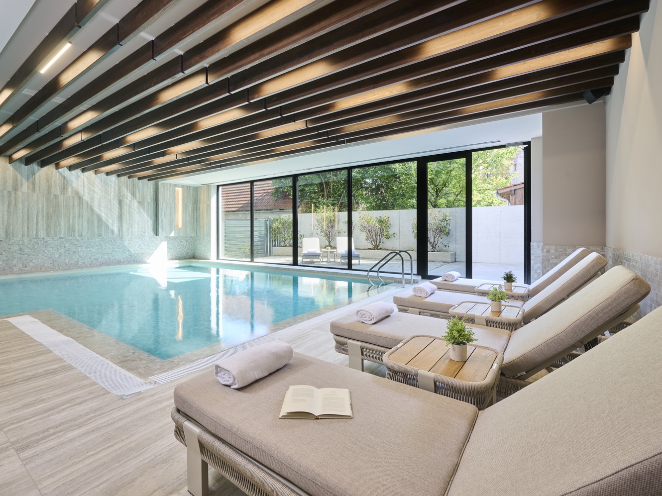Innenpool im Hotel Wellnessbereich mit Liegen und Blick nach draussen
