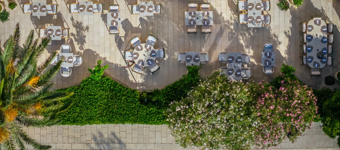 7 Seas restaurant terrace with set tables and Mediterranean greenery
