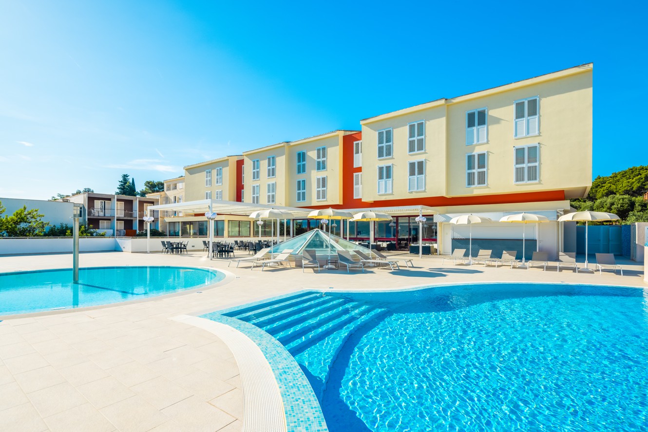 Vanjski pogled na Marko Polo Mardiso Hotel uz bazen, s modernom fasadom i sunčanim vremenom.