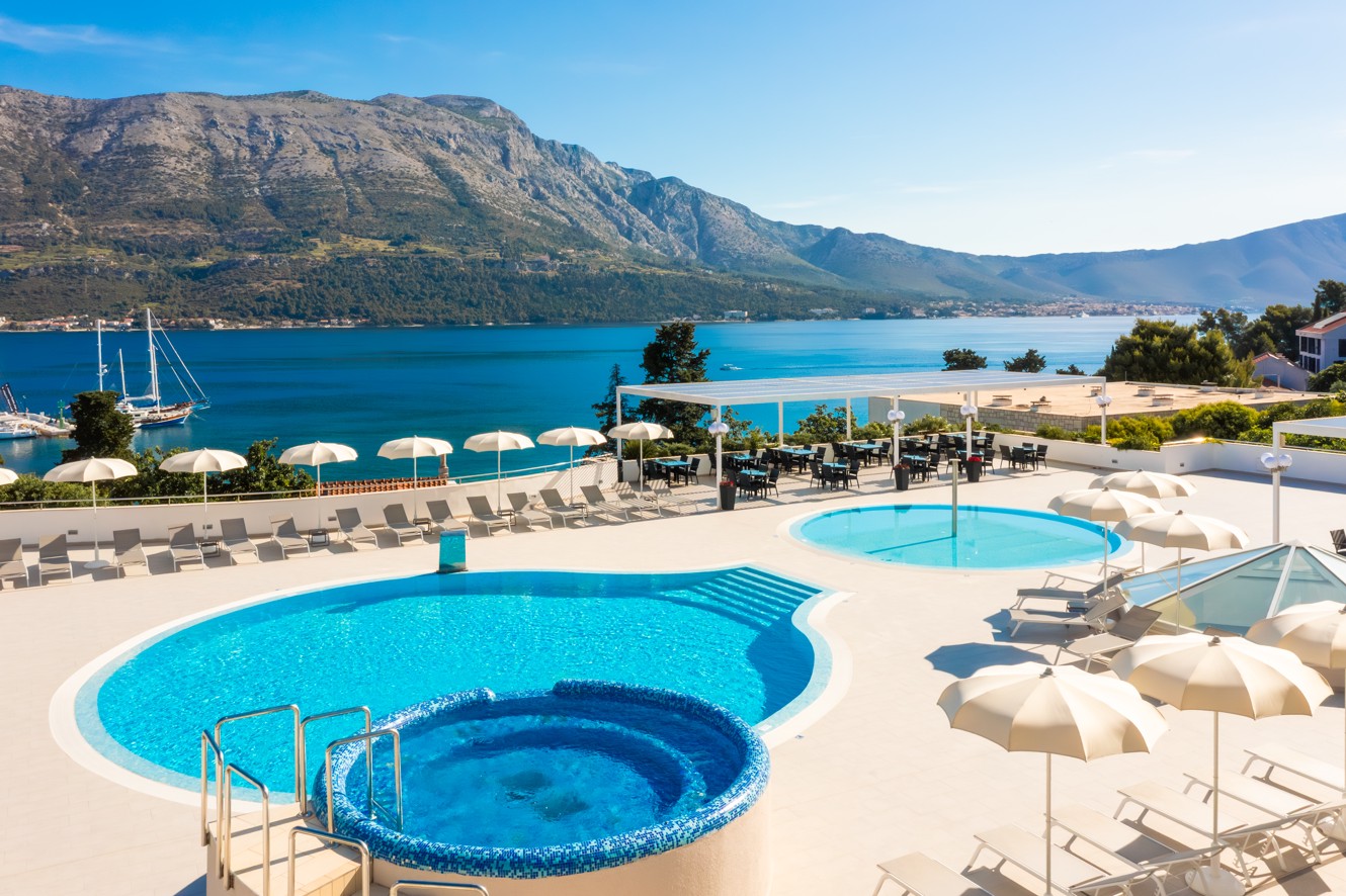 Glavni vanjski bazen hotela Marko Polo Mardiso s ležaljkama i impresivnim pogledom na planine.