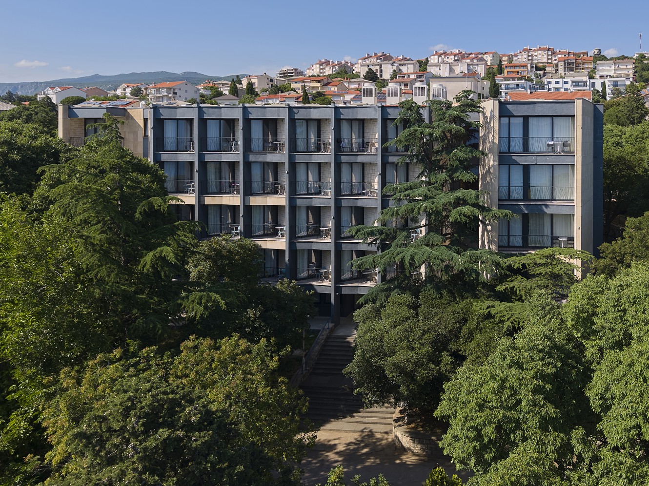 Vista dell’hotel Aminess Vival Casa Lišanj circondato dal verde, con il panorama di Novi Vinodolski sullo sfondo.