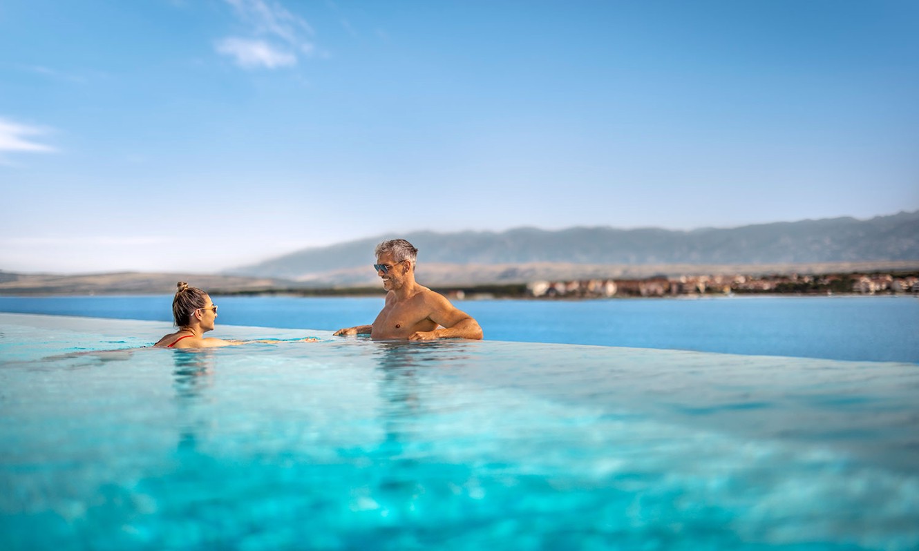 Cople swimming in the relaxing pool with sea view at Aminess Style Camping Avalona resort.
