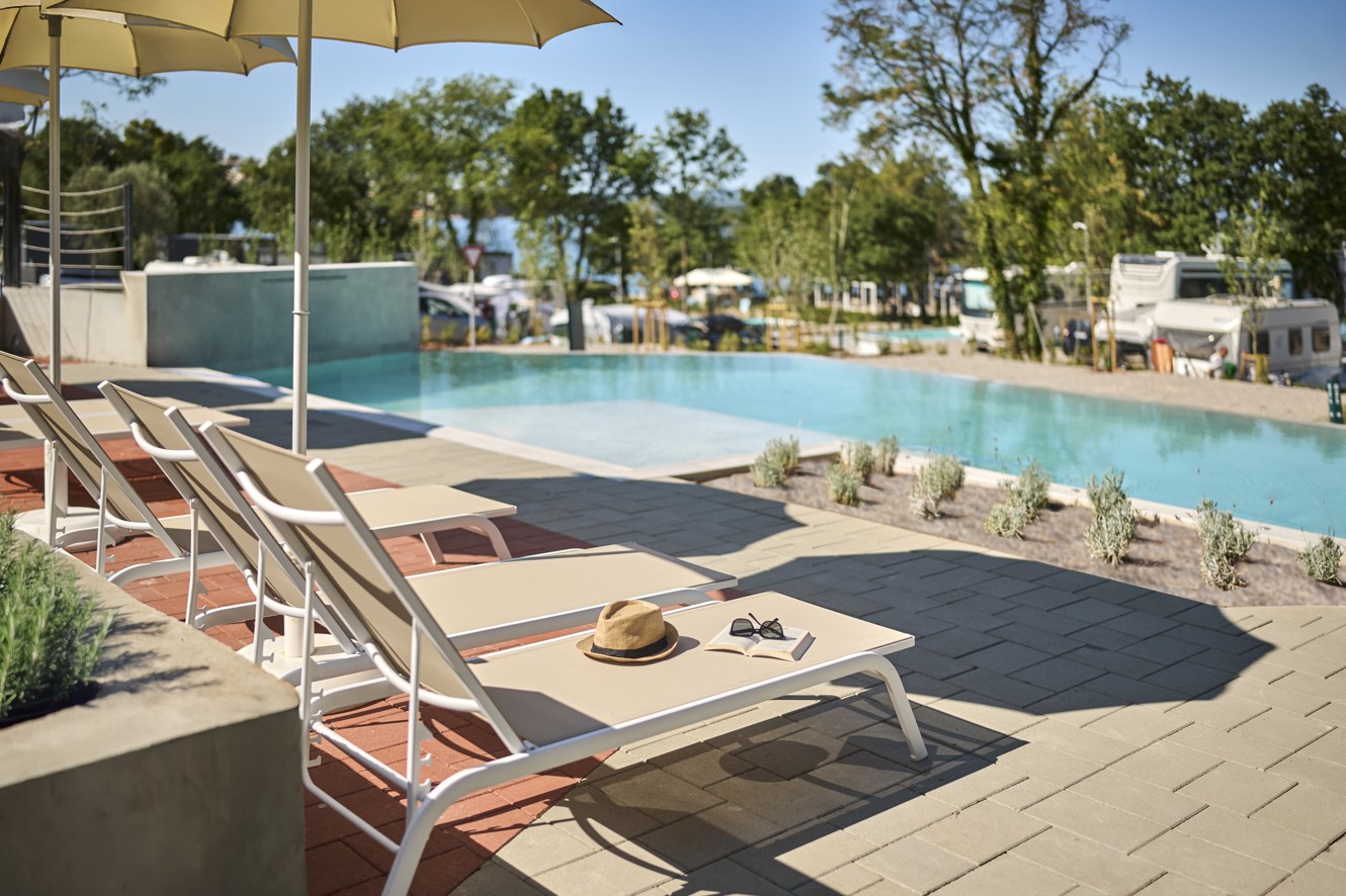 Infinity zwembad met ligstoelen en parasols met uitzicht op het kampeerterrein in Aminess Style Camping Atea Resort.