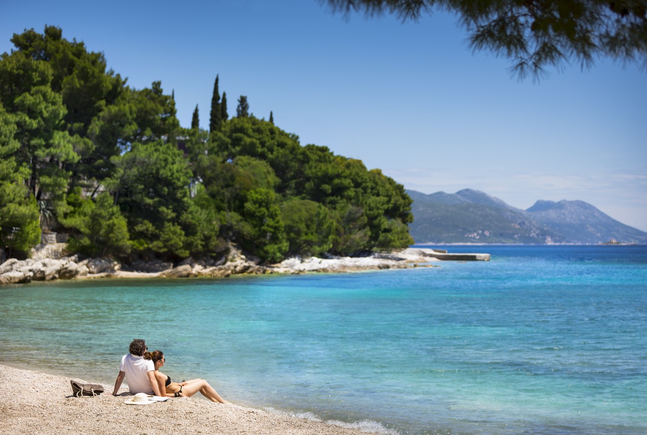 Couple enjyoing sea view on a pebble beach near Aminess Grand Azur Hotel in Orebic.