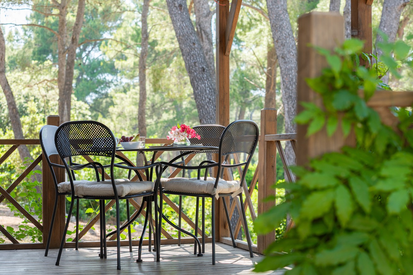 Terrazza rilassante con tavolo e sedie davanti alla casa mobile presso l’Aminess Port9 Planet Camping Resort.