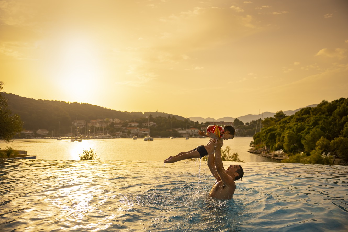A father and son enjoying quality time together at the pool at Aminess Vival Port9 Resort  with a stunning sunset view on the Korcula island in Croatia