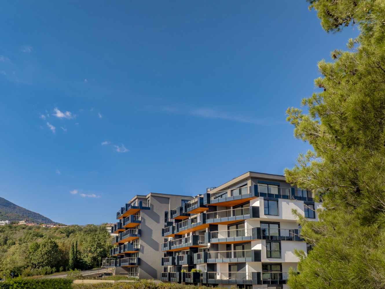 Modern facade of Younique Vollo Residence Opatija surrounded by greenery under clear blue sky