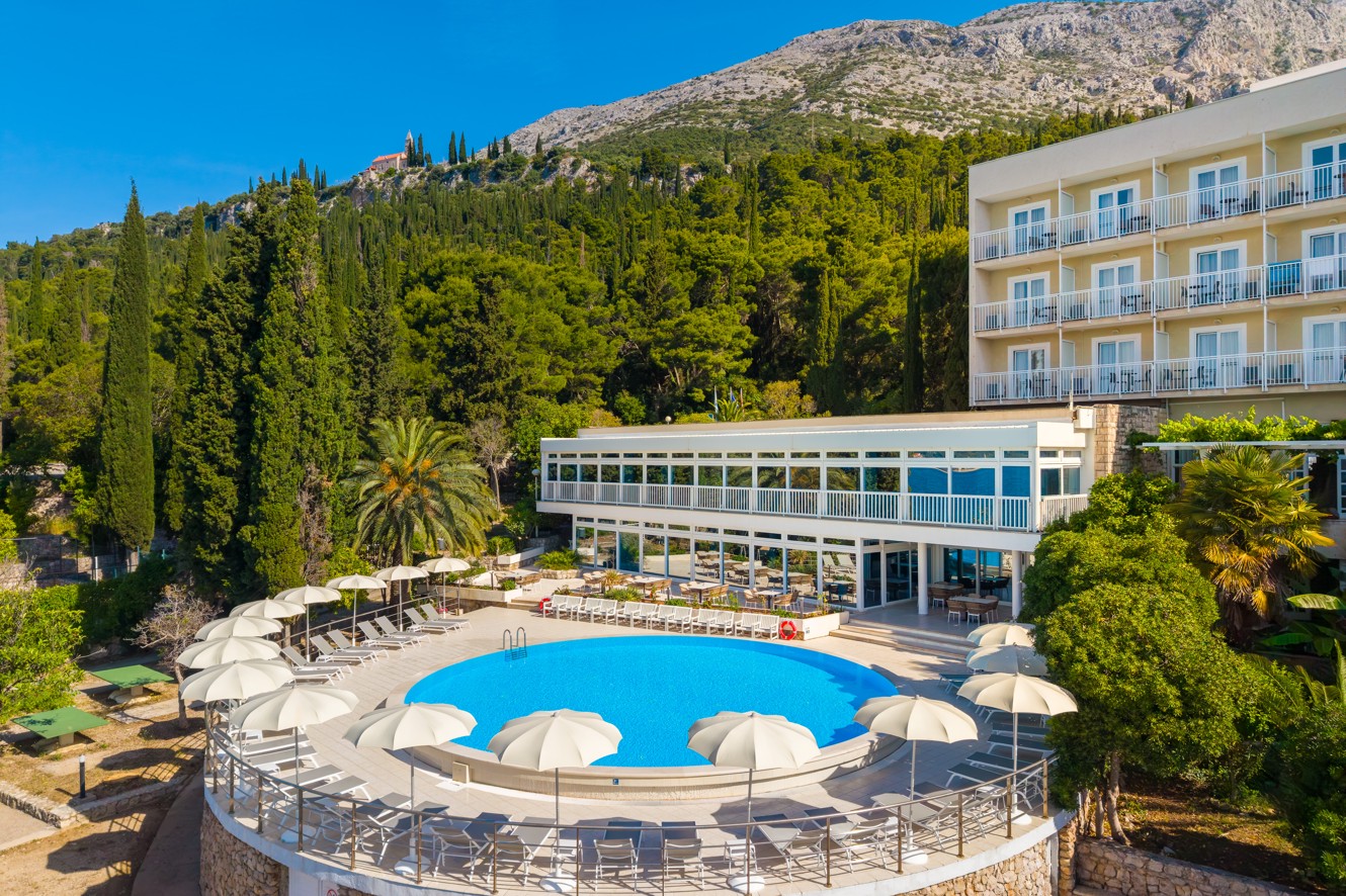 Outdoor pool at Orsan Maradiso Hotel by Aminess with a view of the forested mountain.