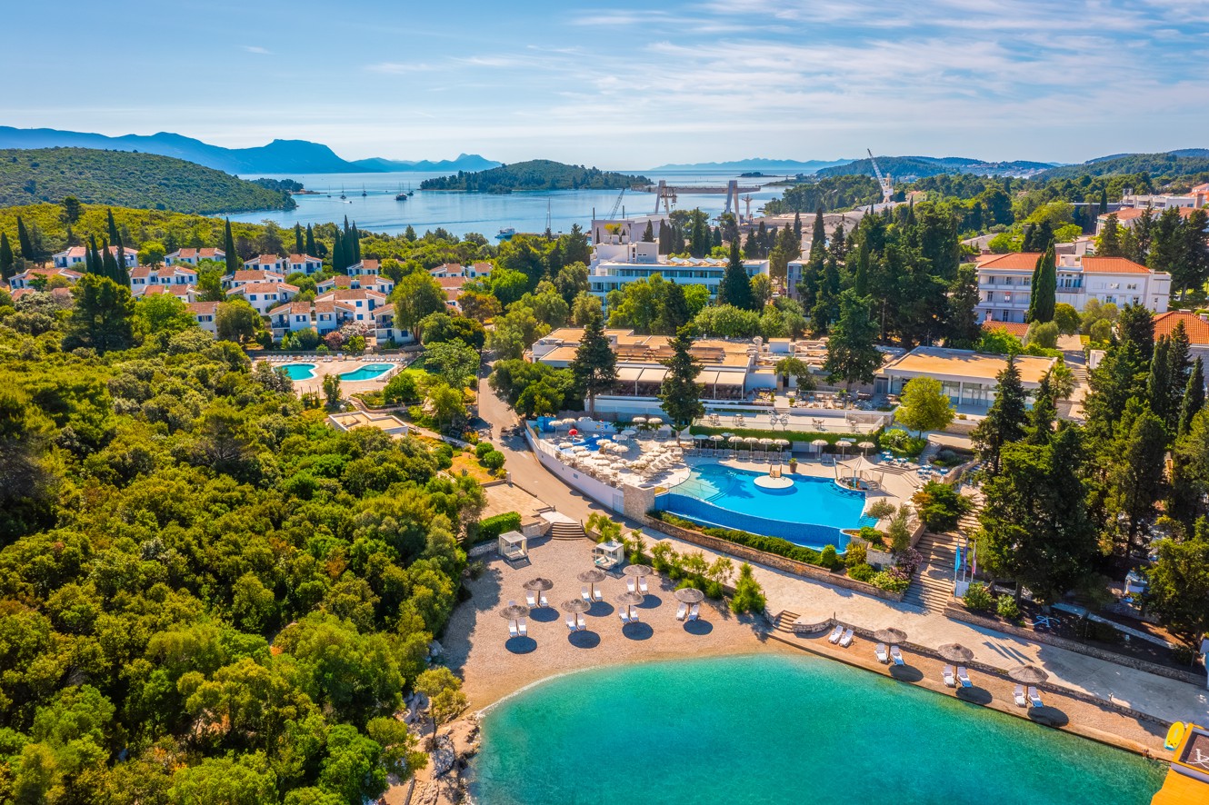 Exterior aerial view of Aminess Vival Port9 Resort, surrounded by greenery and the sea located in a bay on the island of Korcula.