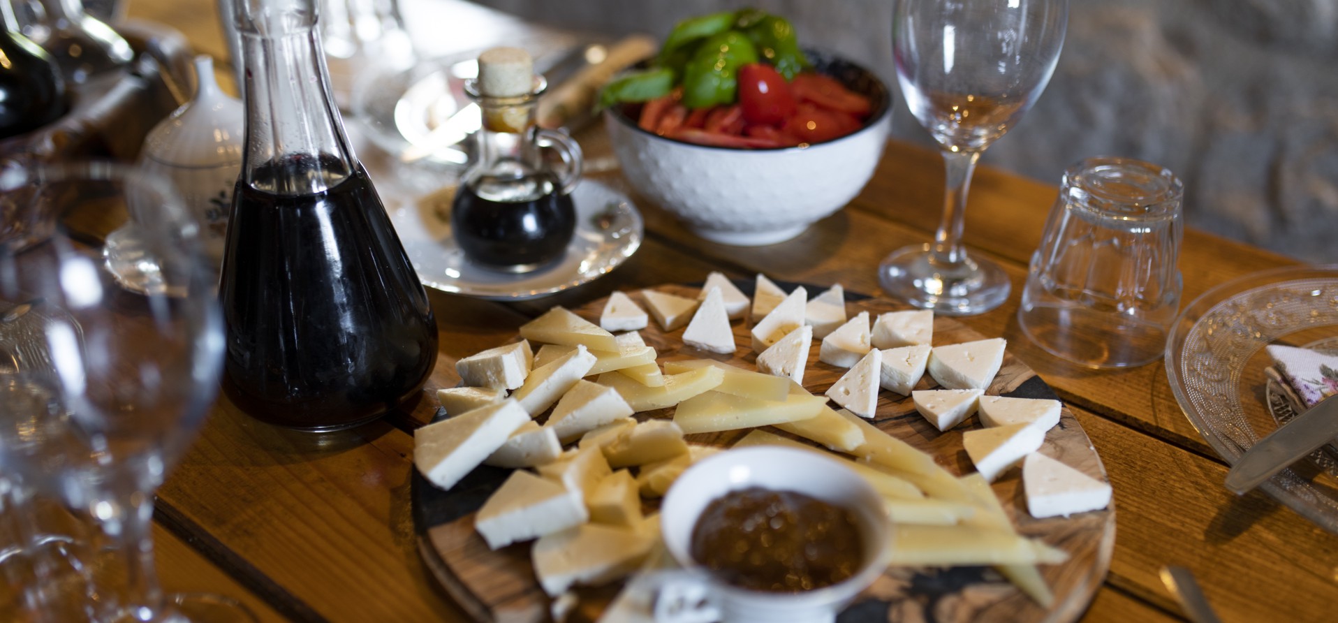 Raznolikost lokalnih proizvoda s otoka Brača, Hrvatska, uključujući teglice s maslinovim uljem, medom i drugim ručno izrađenim proizvodima izloženim na rustikalnom drvenom stolu.