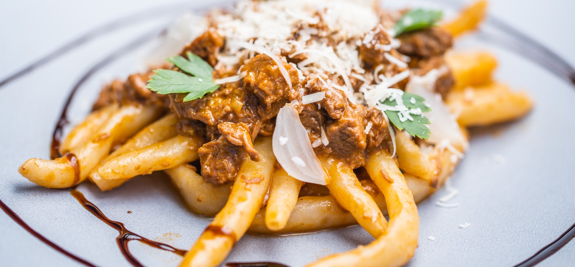 Plate of Zrnovski makaruni pasta topped with rich meat sauce and cheese, a local Korcula specialty.