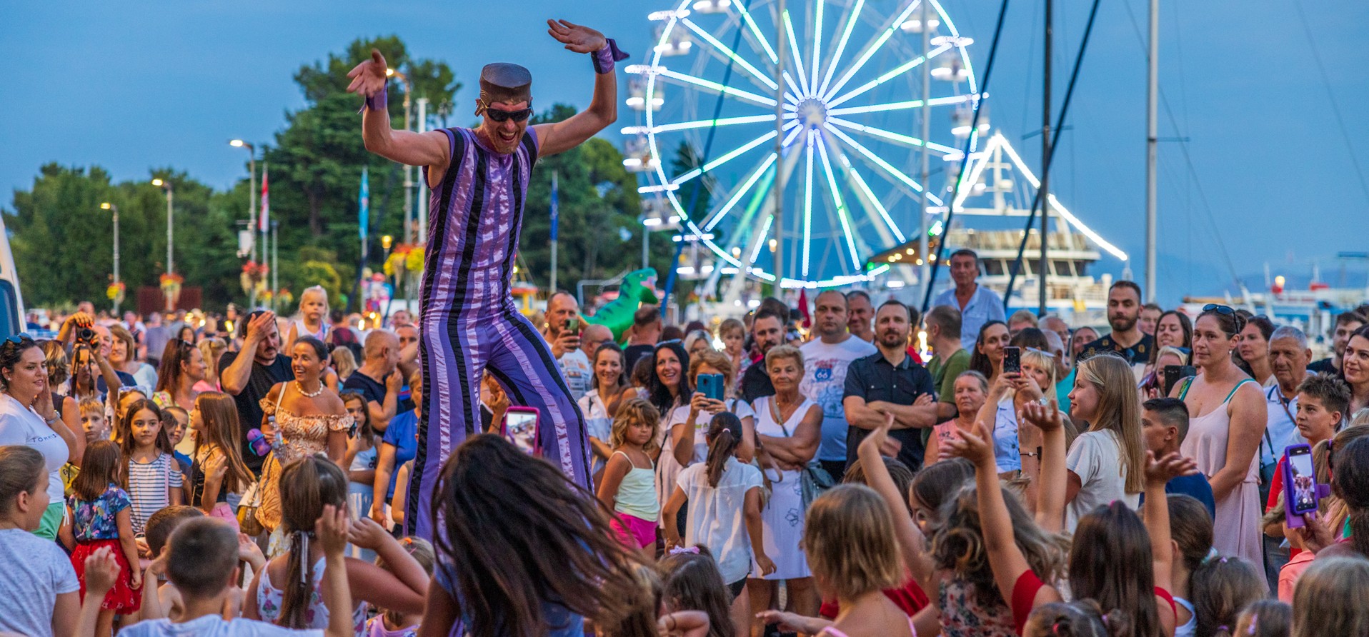 CrikvArt Veranstaltung in Crikvenica mit einer lebhaften Menge, Künstlern und einem Riesenrad im Hintergrund.