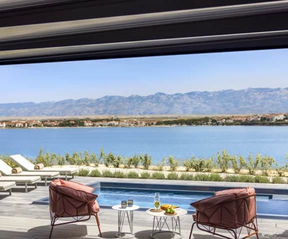 Elegantna privatna terasa s bazenom, lounge namještajem i panoramskim pogledom na more i planine u pozadini.
