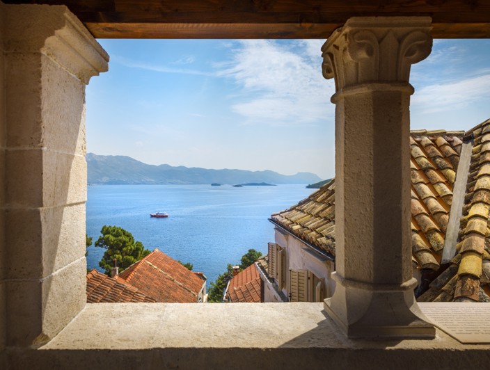 Scenic Adriatic Sea view framed by historic stone windows from Marko Polo Tower in Korcula Old Town.
