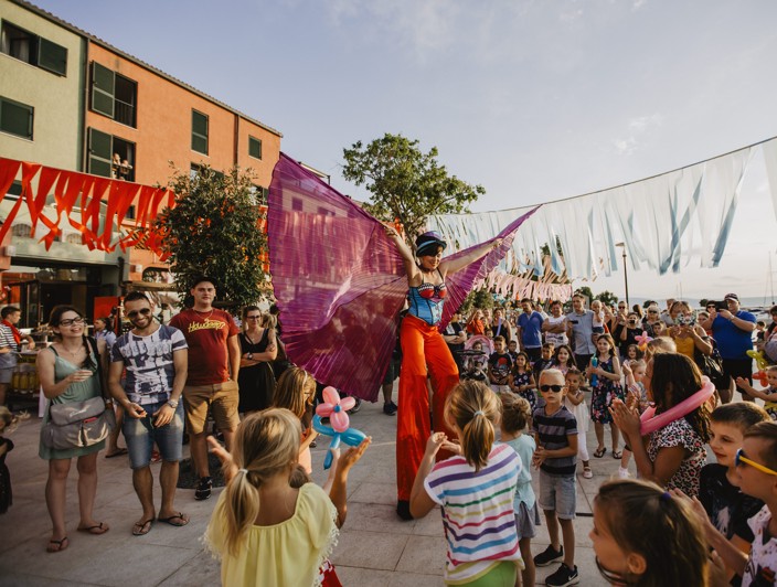 Family-friendly festival with colorful decorations and a crowd on Krk Island, Croatia.