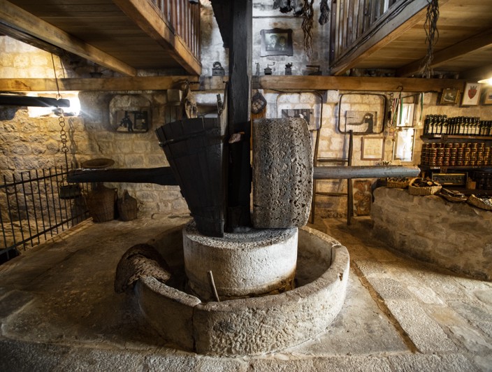 Tradicionalna proizvodnja maslinovog ulja na otoku Braču, Hrvatska, s opremom za prešanje maslina i bocama svježe prešanog maslinovog ulja.