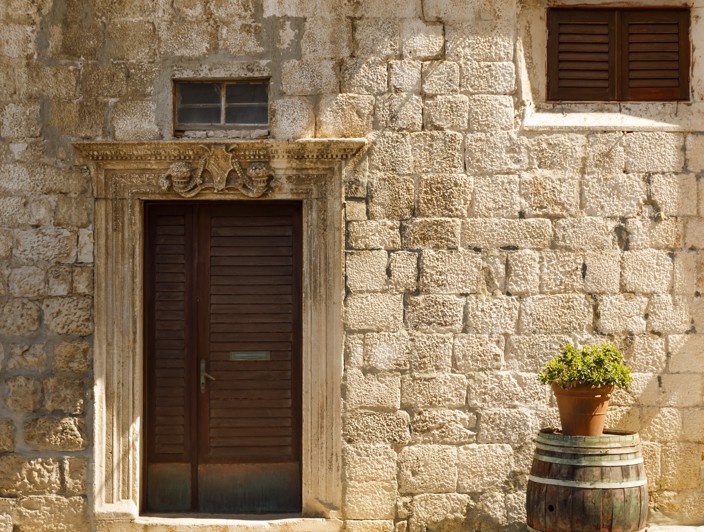 A historic stone house with traditional architecture and a rustic wooden door in Korcula Old Town.