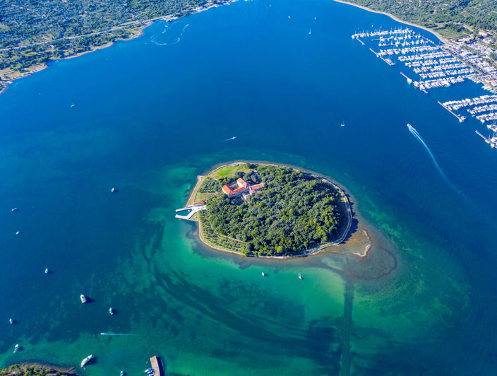 Aerial view of Košljun Island near Krk, Croatia, featuring the historic monastery surrounded by turquoise sea.