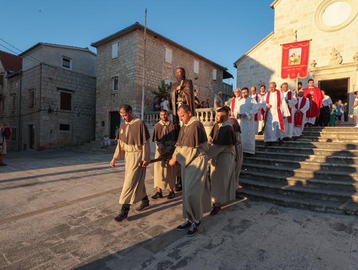 Una processione religiosa sull'isola di Brač, Croazia, con partecipanti in abiti tradizionali che camminano per le strade, celebrando le tradizioni culturali e spirituali locali.