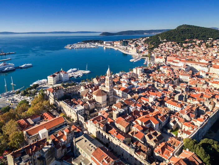Bild von der malerischen Aussicht auf Split, Kroatien, mit historischer Architektur, einer belebten Uferpromenade und der Adria, wie sie von der Insel Brač aus zu sehen ist.