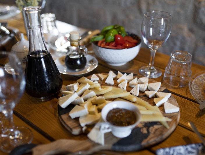 Raznolikost lokalnih proizvoda s otoka Brača, Hrvatska, uključujući teglice s maslinovim uljem, medom i drugim ručno izrađenim proizvodima izloženim na rustikalnom drvenom stolu.