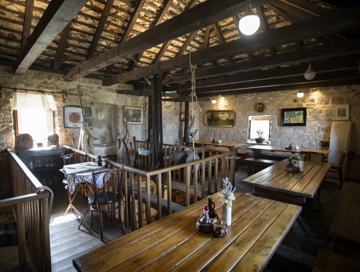 Rustikalno područje na otoku Braču, Hrvatska, s postavljenim drvenim stolovima za iskustvo kušanja maslinovog ulja, prikazujući tradicionalne metode proizvodnje otoka.