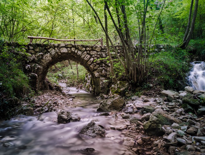 Oude stenen brug in het bos van de Kvarner boven een beek en waterval, een verborgen natuurlijke en historische bezienswaardigheid