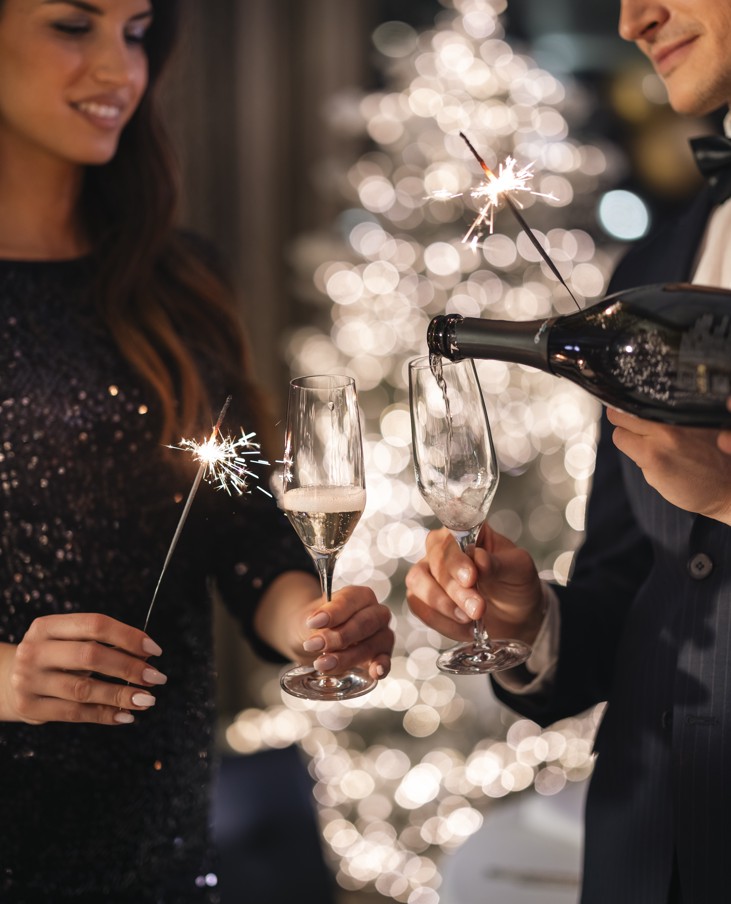 Elegante festa di Capodanno con due persone che brindano con champagne e tengono stelline in un’atmosfera festiva.