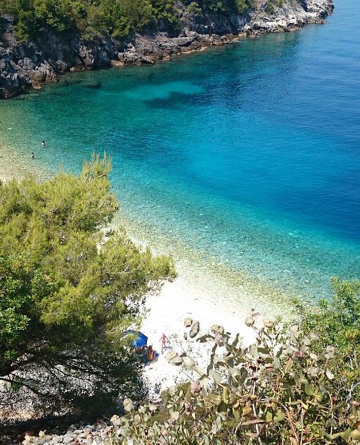 Vista sulla spiaggia di ciottoli Vaja con mare cristallino e coste verdi