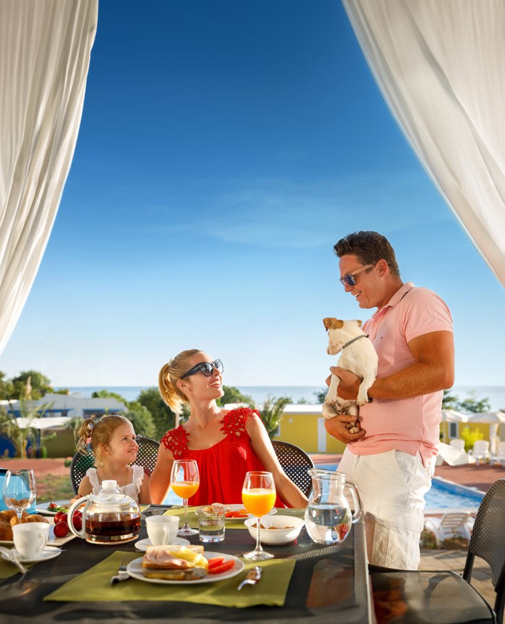 Famiglia che si gode una colazione primaverile sul mare durante le vacanze di Pasqua
