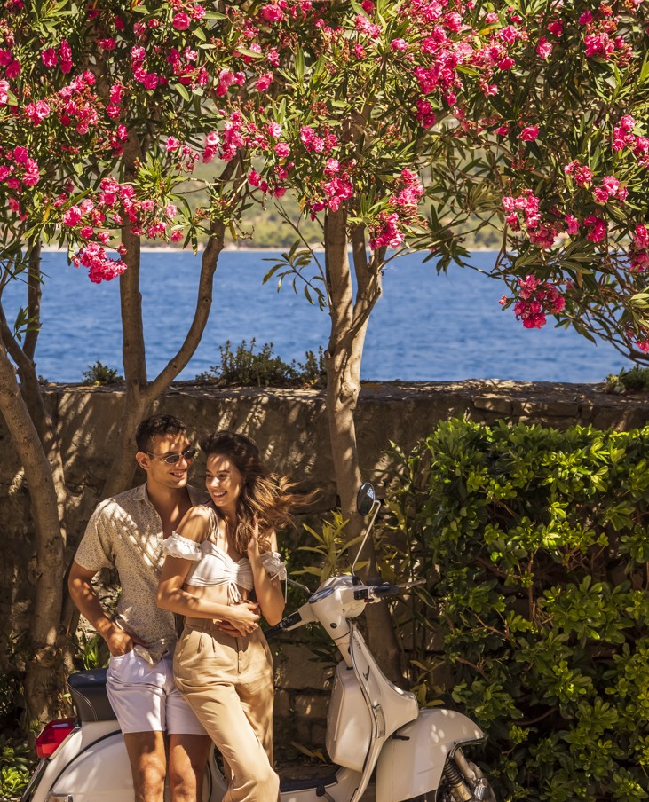 Couple enjoying a relaxed walk along the Korčula city promenade surrounded by Mediterranean greenery and the sea