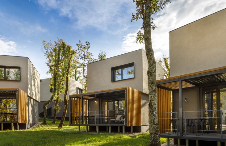 Exterior view of Aminess Younique Gaia Green Villas surrounded by trees, showcasing modern architecture and natural integration.