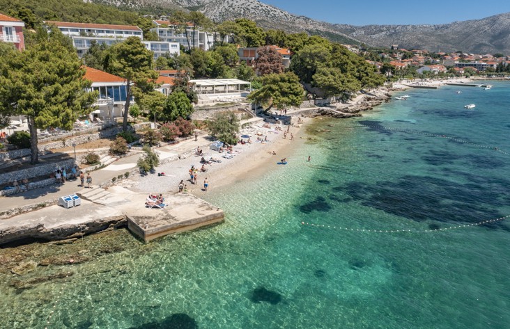 Luftaufnahme vom Strand in der Nähe von Aminess Maradiso Casa Bellevue, mit kristallklarem türkisfarbenem Wasser und lebendigem Grün.