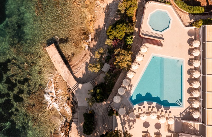 Pogled iz ptičje perspektive na Aminess Younique Bellevue Hotel smješten među bujnim zelenilom, s privatnom plažom i izravnim pristupom moru.