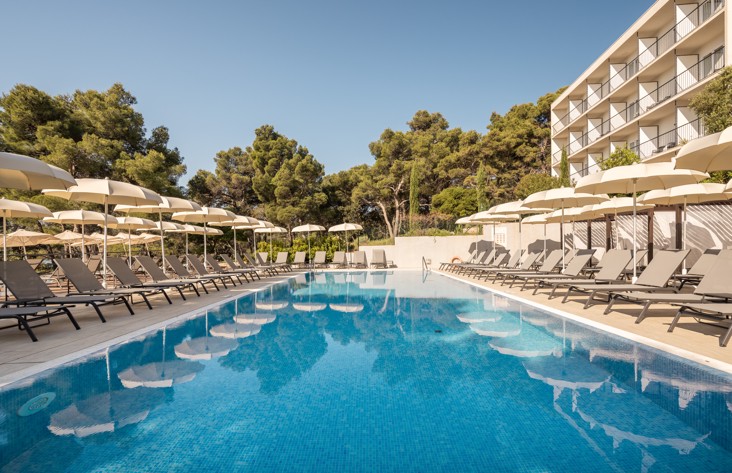 Pool surrounded by sun loungers at Aminess Younique Senses Resort on Hvar, ideal for summer relaxation.