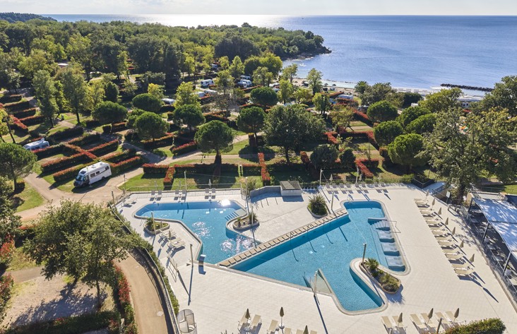 Vista panoramica della piscina e della spiaggia presso Aminess Planet Camping Maravea Resort, circondato dal verde, luogo perfetto per rilassarsi e godersi la vacanza