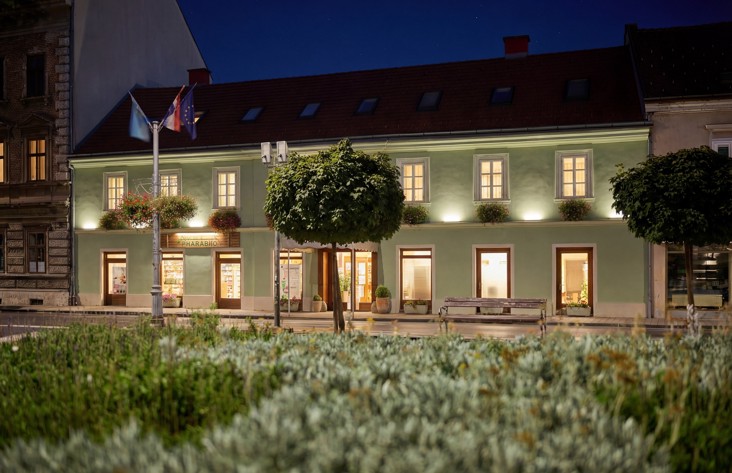 Aminess hotel in Karlovac at night with illuminated facade and park in front