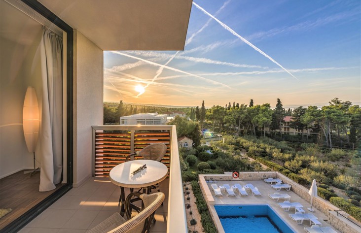 View from the terrace with a swimming pool below and garden in the distance at Aminess Vival Velaris Resort Brač