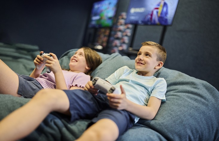 A boy and a girl relax while playing console video games in the gaming room