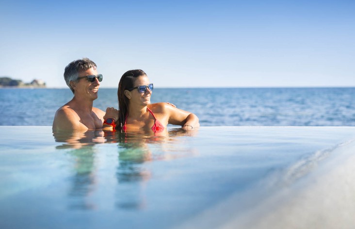 Ein Paar genießt die Aussicht am Rand des Infinity-Pools.