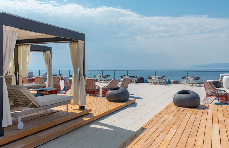 Sunčana terasa Aminess Vollo Residences s ležaljkama i pogledom na more.