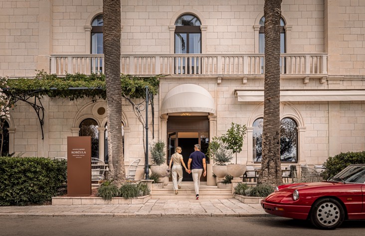 A couple enters Younique Korcula Heritage Hotel through its stone entrance.