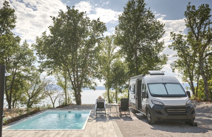 Območje bazena v Aminess Style Camping Atea Resort z ležalniki in bujnim drevesjem.