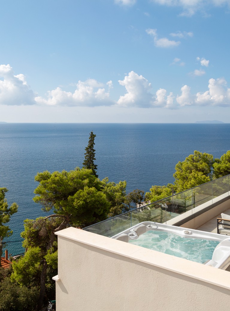 Terasa v Aminess Alfir Resortu z zasebnim jacuzzijem in odprtim pogledom na morje, obdana z mediteranskim zelenjem