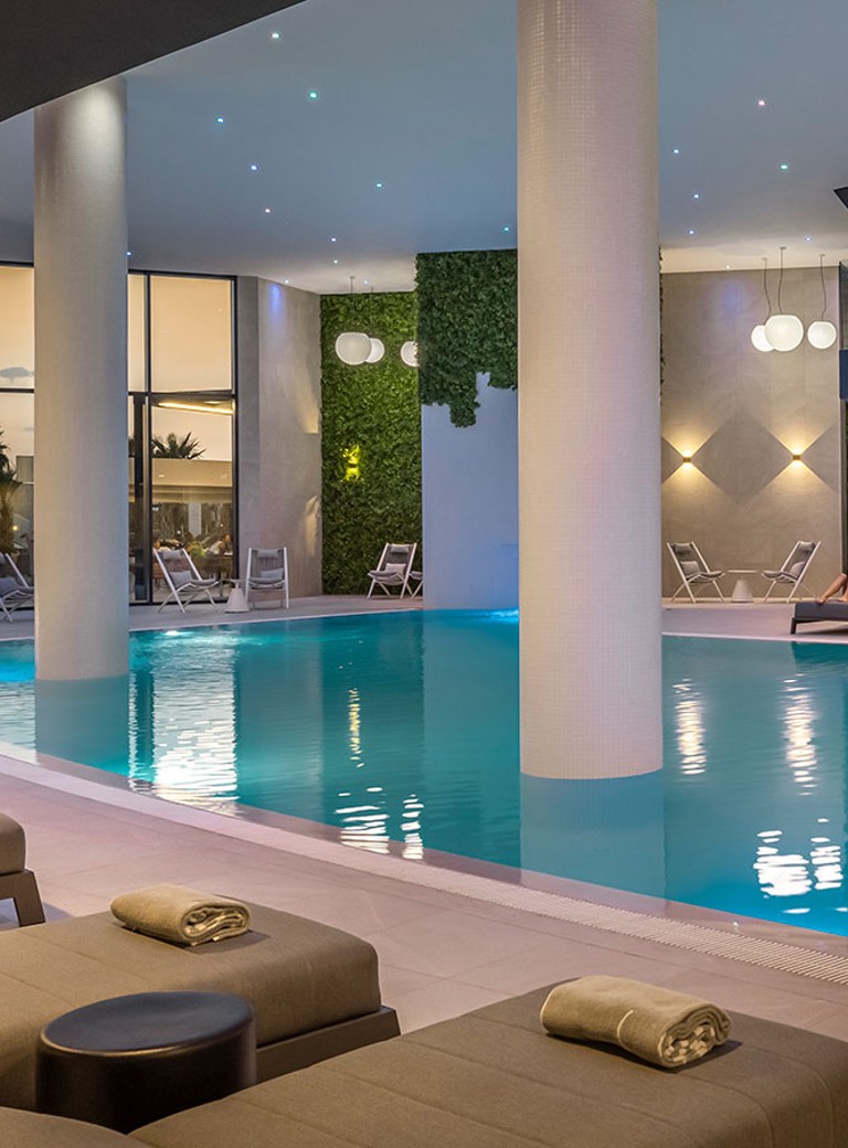 Kryty basen spa Aminess Khalani z leżakami i spokojnym oświetleniem.