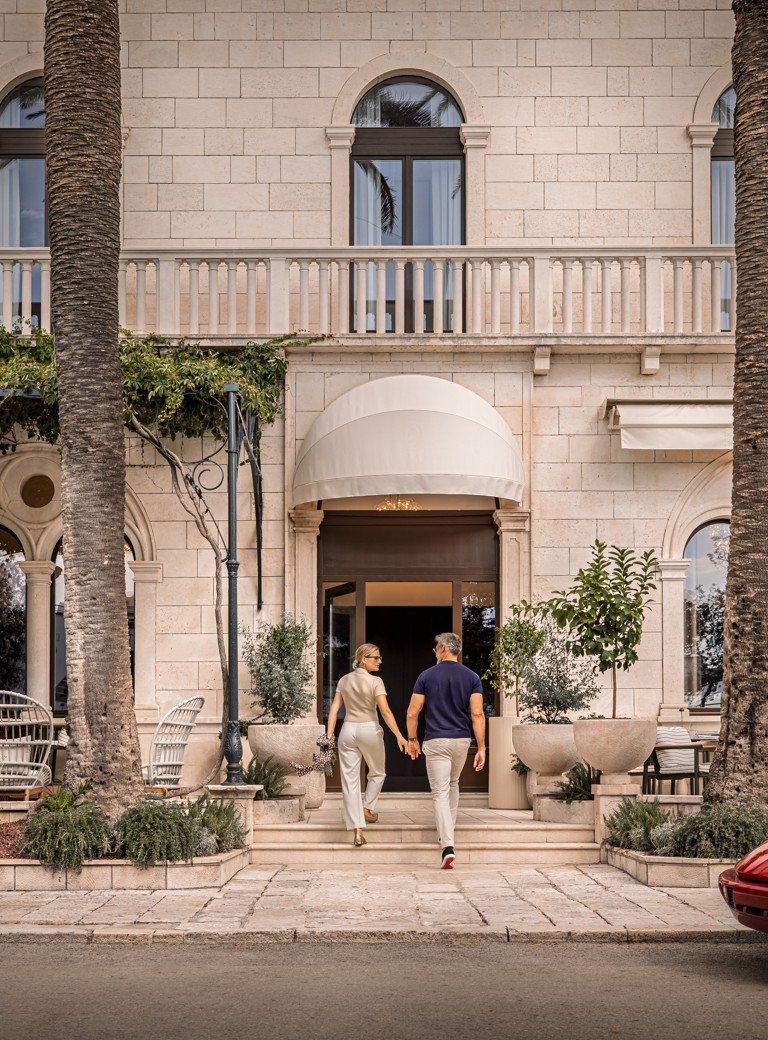 A couple enters Younique Korcula Heritage Hotel through its stone entrance.
