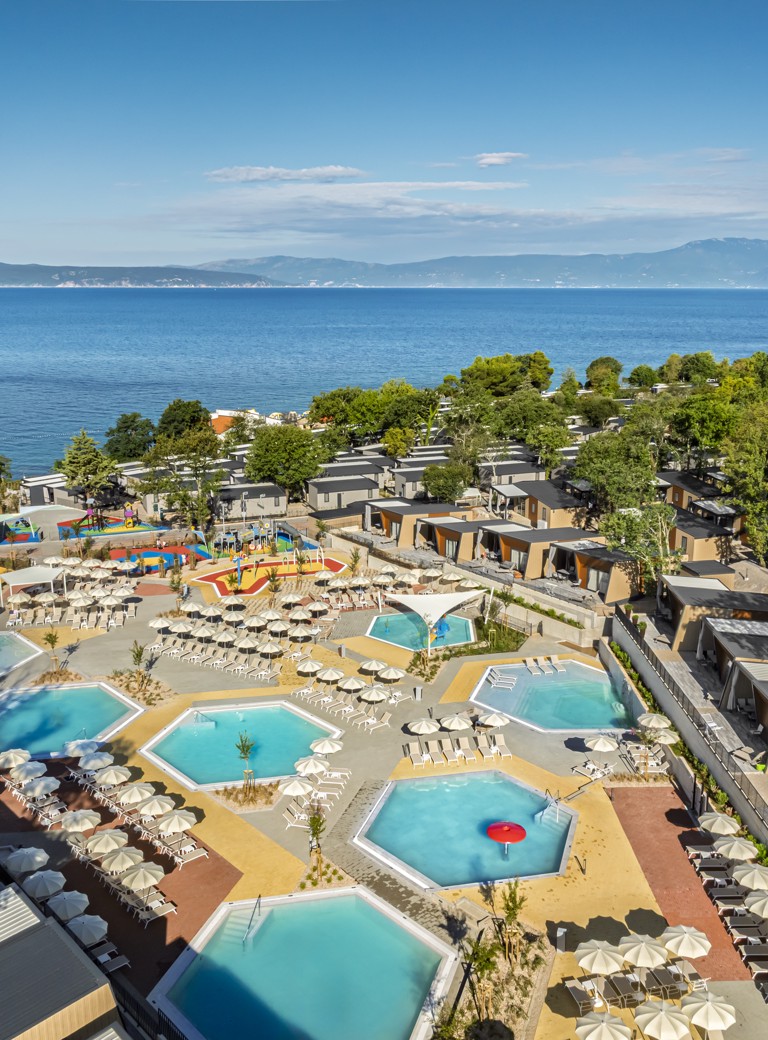 Vista aerea della zona piscine e delle case mobili dell'Aminess Style Camping Atea Resort, con mare e costa sullo sfondo.