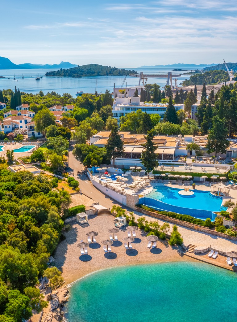 Zunanji zračni pogled na Aminess Vival Port9 Resort, obdan z zelenjem in morjem, ki se nahaja v zalivu na otoku Korčula.